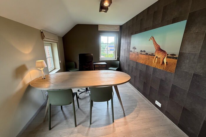 Een moderne kantoorkamer met een houten tafel, groene stoelen, een zwarte bureaustoel en een opvallende giraffefoto-perfect voor inspiratie huis kijkwoning Blavier Thorembais-Saint-Trond of je volgende bezoek kijkwoning Thorembais-Saint-Trond Blavier.