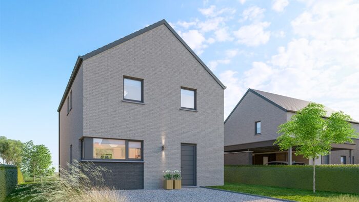 Cette charmante villa de Gerpinnes est une maison moderne en briques grises de deux étages avec un toit en pente. Elle dispose d'une porte d'entrée avec une petite jardinière adjacente. L'allée de gravier mène à un jeune arbre et à une haie dans le jardin, le tout sous un ciel partiellement nuageux.
