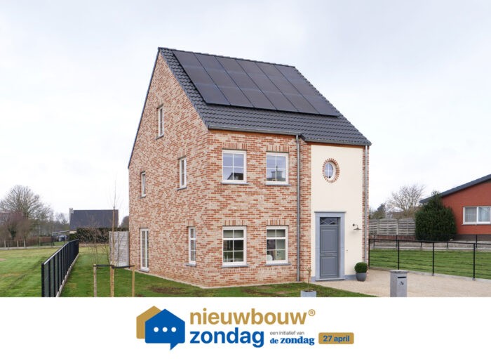Een modern bakstenen huis met twee verdiepingen, een grijze deur en zonnepanelen op het dak. Er is een klein, rond raam boven de deur. Op de achtergrond zijn een stukje gras en een ander huis te zien. Onderaan staat de tekst 'nieuwbouw zondag'.