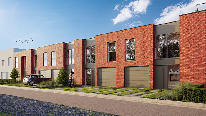 Maisons mitoyennes modernes en briques à deux étages avec de grandes fenêtres, des portes de garage et une cour avant bien entretenue avec de l'herbe et des arbustes. Un couple se tient dans l'allée. Une voiture est garée à proximité et une volée d'oiseaux vole dans le ciel bleu.