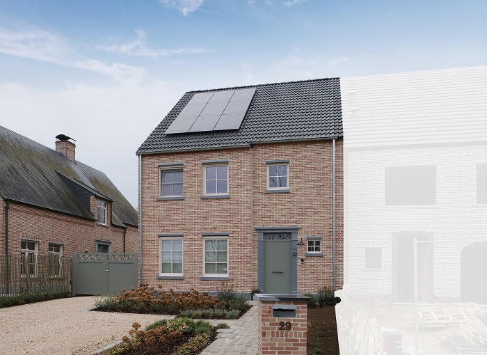 Een bakstenen huis van twee verdiepingen met zonnepanelen op het donkere pannendak, lichtgrijze deuren en raamkozijnen, een kleine voortuin met planten en een oprit die leidt naar een grijs hek. Het huisnummer 29 is zichtbaar op de brievenbus.