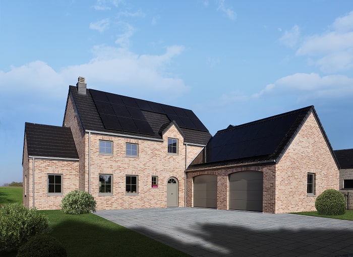 Une maison moderne de deux étages en briques avec des tuiles noires et des panneaux solaires, à côté d'un garage double détaché également avec des panneaux solaires. L'allée est pavée et il y a quelques buissons sur la pelouse. Le ciel est bleu avec quelques nuages.